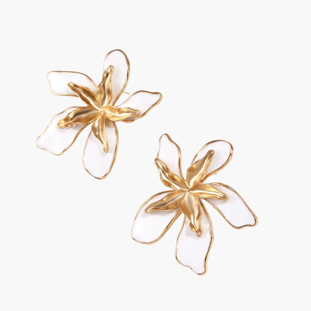 White enamel tropical flower earrings with sculptural gold-plated center and organic petal design on cream background