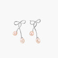 Rhodium-plated silver earrings with organic vine curves and two peachy freshwater pearls on cream background