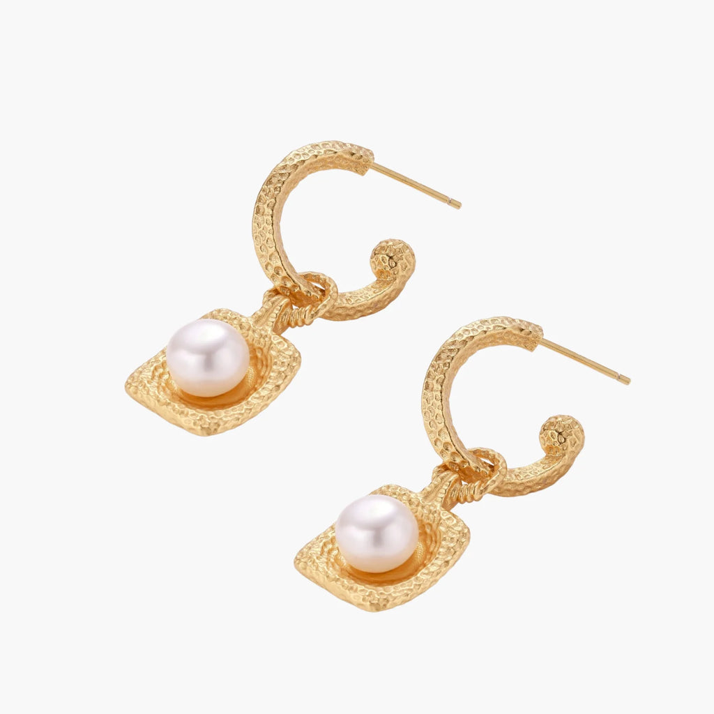 Pair of gold vermeil hoop earrings with textured square frames holding freshwater pearls on cream background