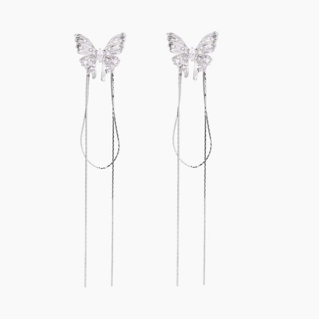 Pair of silver threader earrings with crystal butterfly tops and long chain drops on cream background.