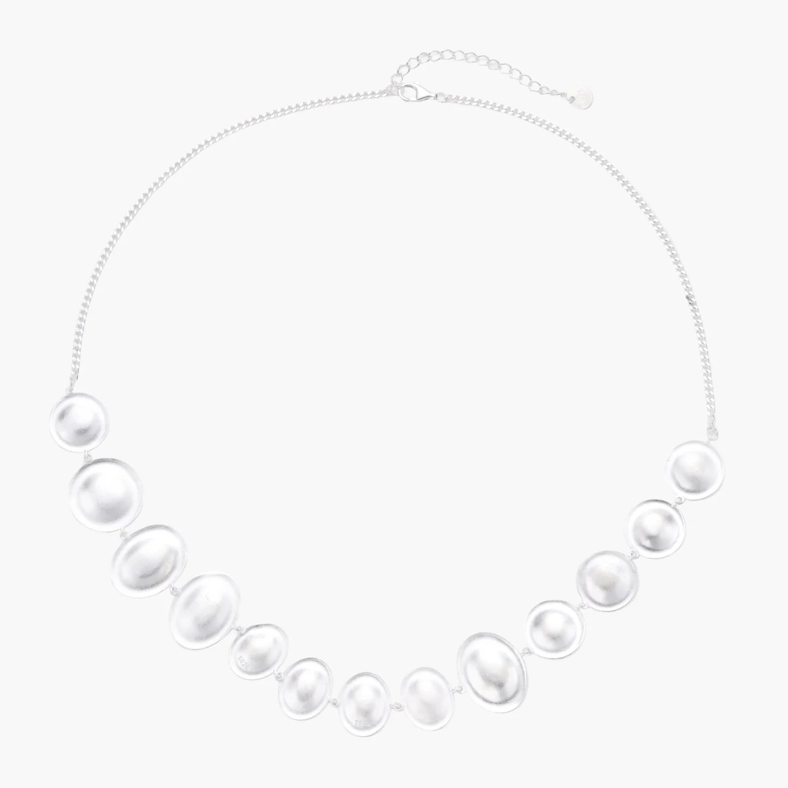 Graduated pearl-finish silver discs forming an organic bubble bib necklace on delicate chain against cream background.