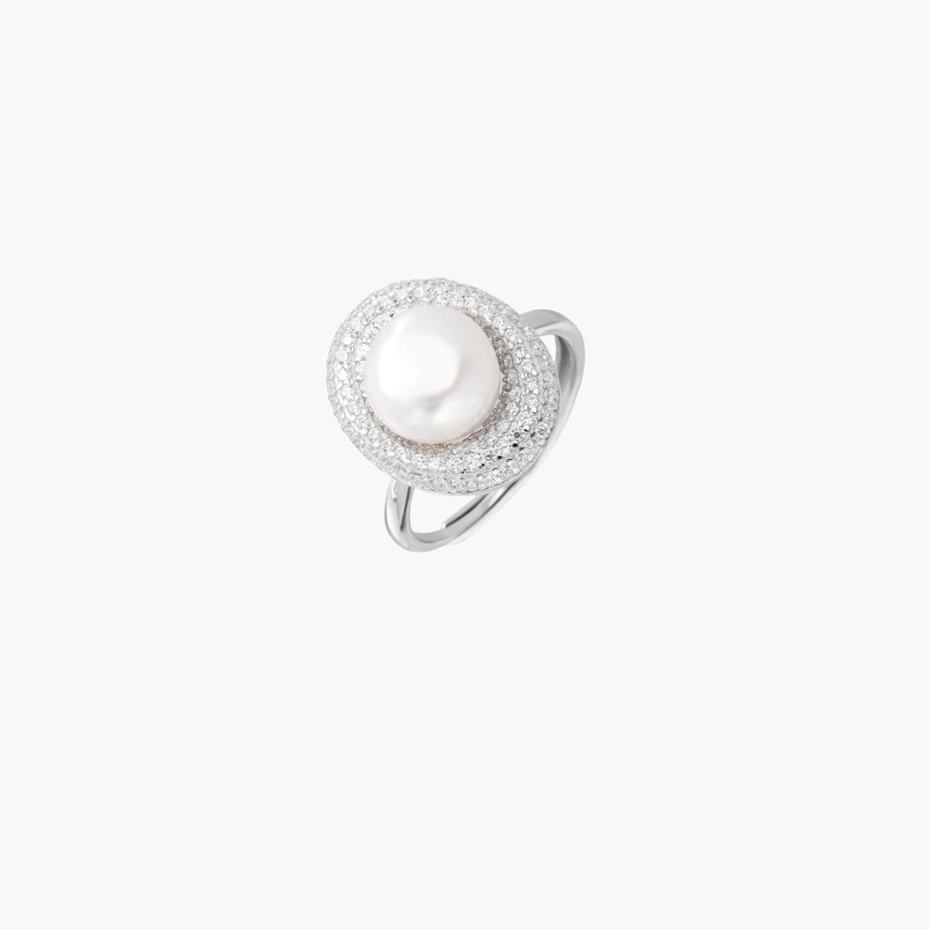 Silver ring with lustrous white pearl center surrounded by sparkling crystal halo on light background.