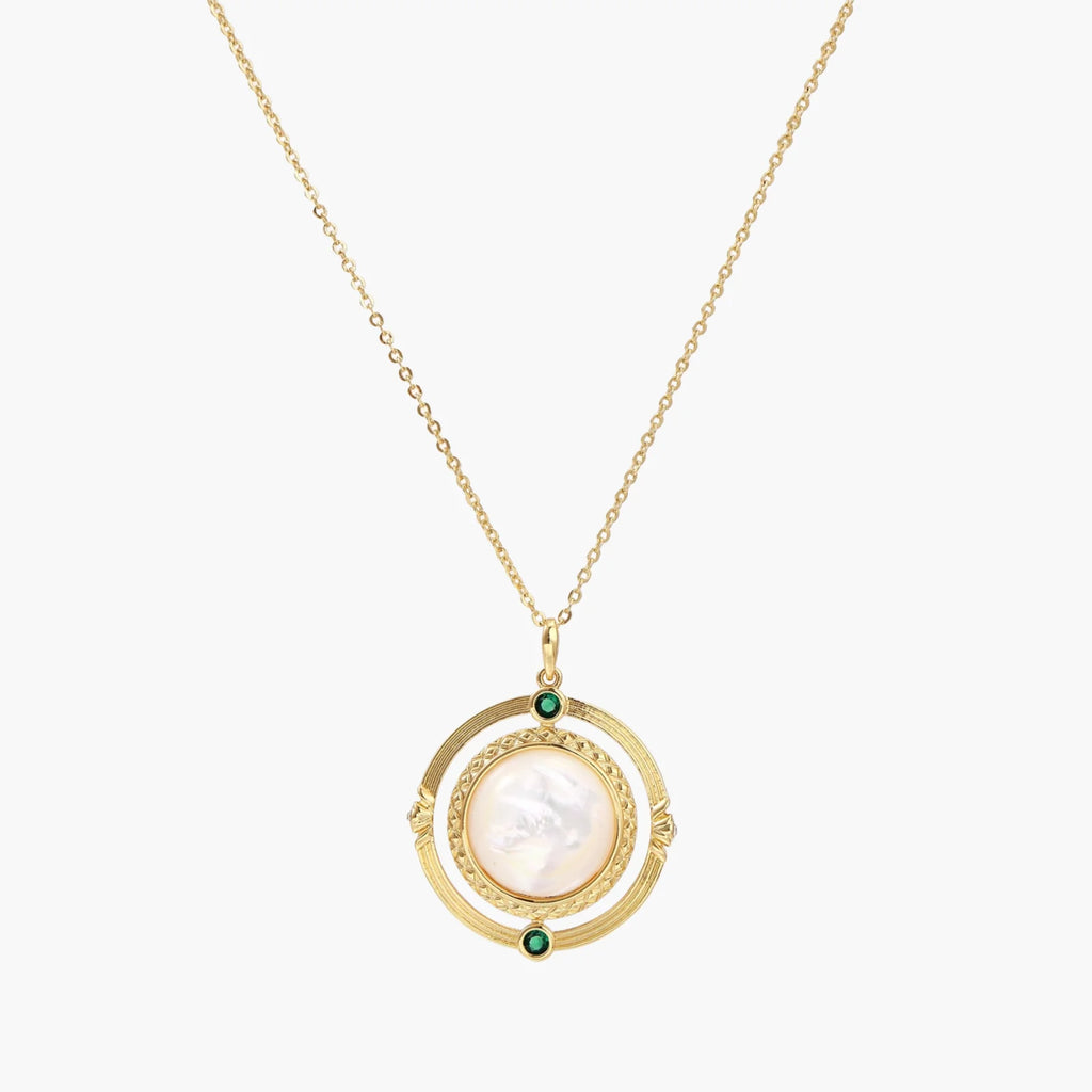 Gold pendant necklace with circular orbital design, iridescent mother-of-pearl center, and green zirconia accents