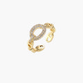 Gold-plated brass chain link ring with one oval CZ-pavé segment on cream background, adjustable cuff style.