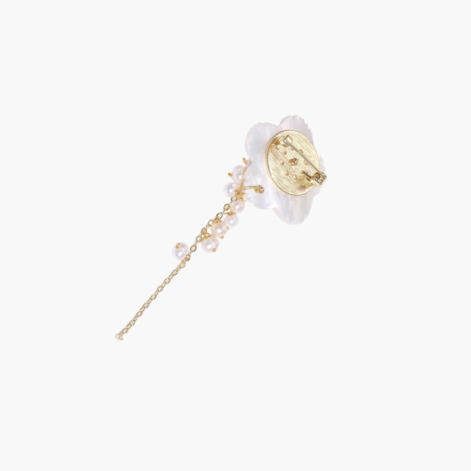 Iridescent shell flower brooch with carved petals and cascading freshwater pearls on gold chain against cream background.