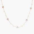 Gold vermeil chain with iridescent star-shaped baroque pearls and small round freshwater pearl drops on cream background.