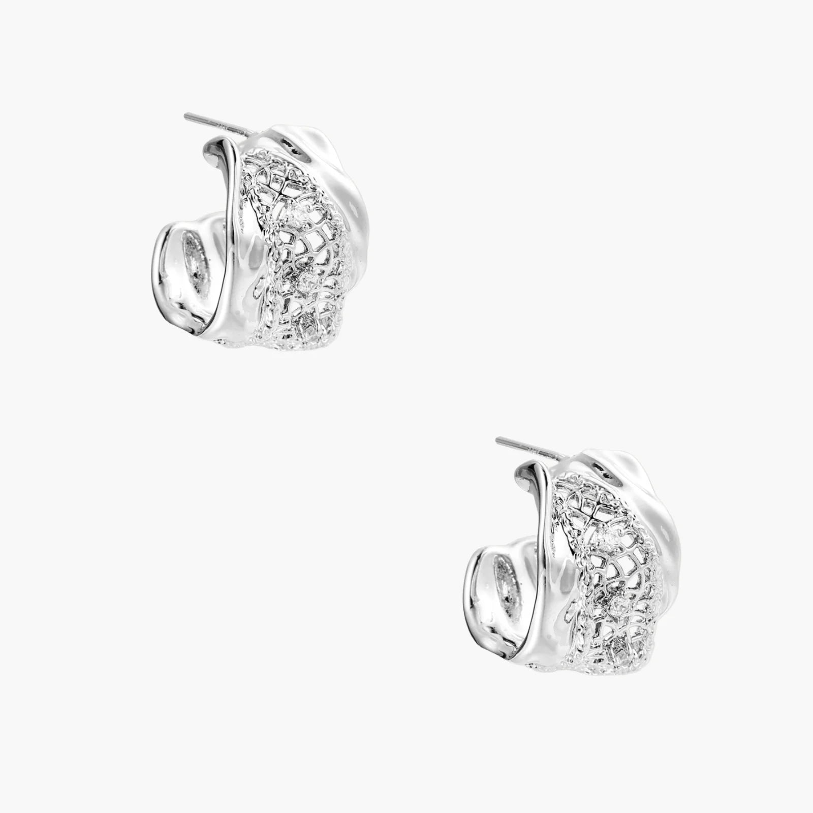 Close-up of sculptural hoop earrings with lattice center band and smooth twisted edges in white gold-plated brass with zirconia