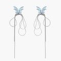 Long silver-tone earrings with powder blue enamel butterfly studs and flowing chain tassels on cream background