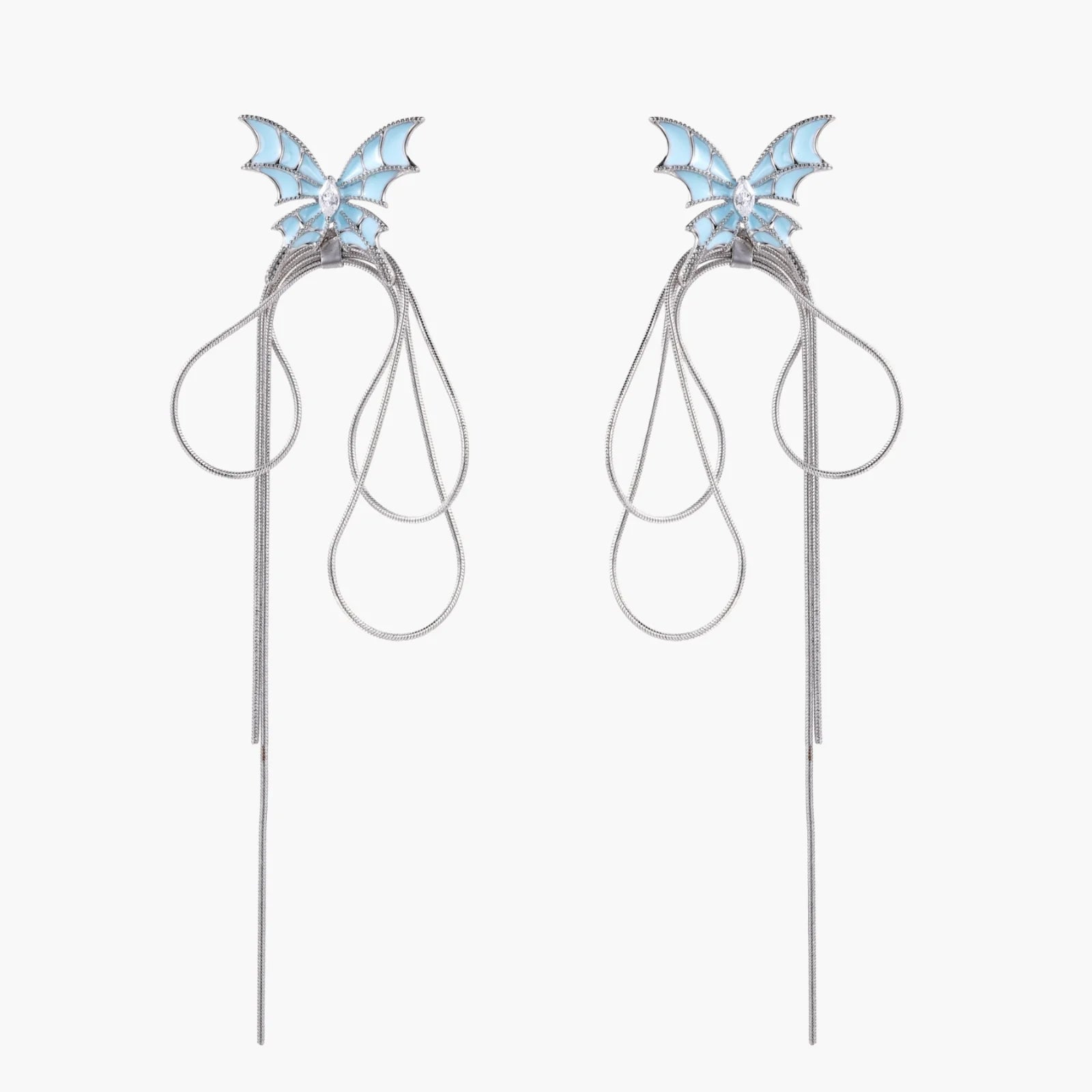 Long silver-tone earrings with powder blue enamel butterfly studs and flowing chain tassels on cream background