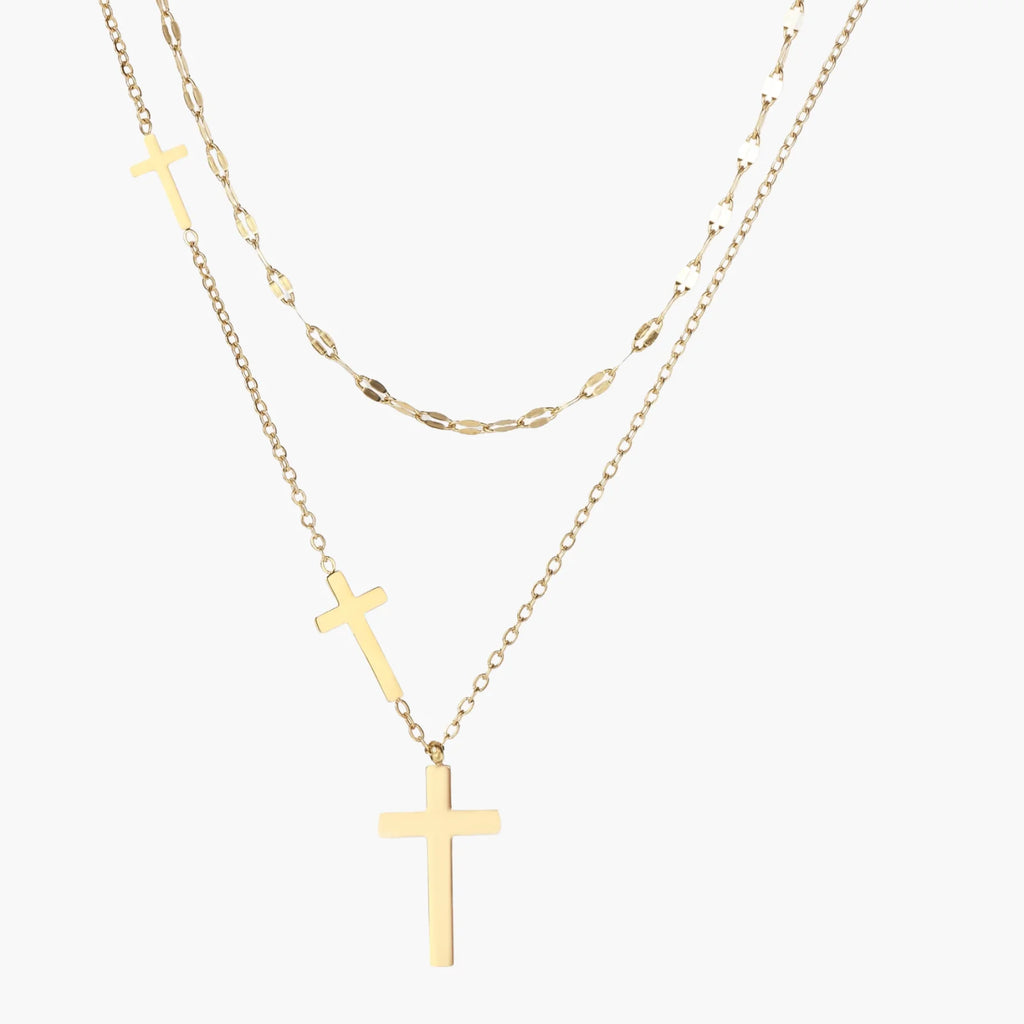 Three-layered gold necklace set with graduated cross pendants in mixed chain styles on white background.