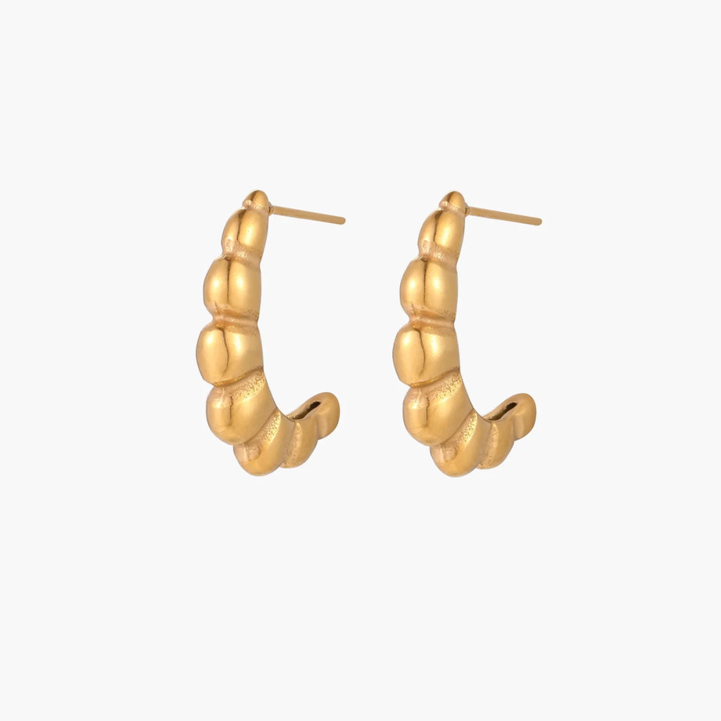 Gold-plated sculptural hoop earrings with chunky segmented design on cream background