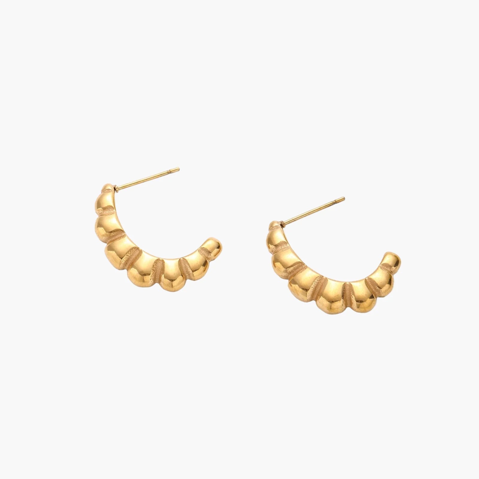 Gold-plated sculptural hoop earrings with chunky segmented design on cream background