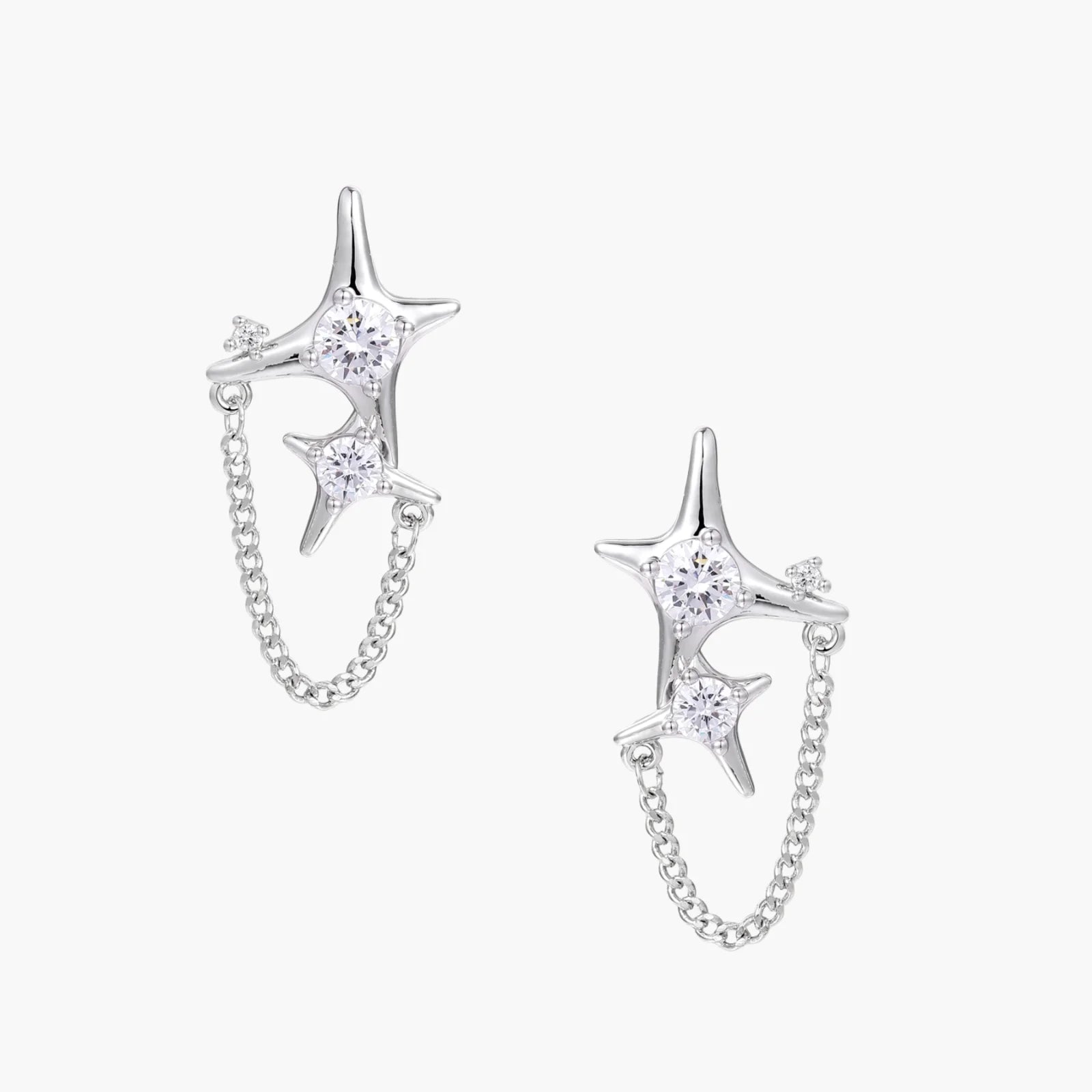 Silver star studs with crescent moon cutouts and zirconia stones connected by delicate chains on white background