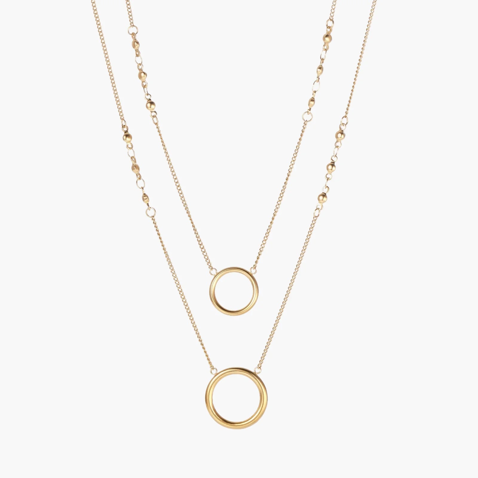 Layered gold necklace set with two open circle pendants and mixed chain styles on beige background