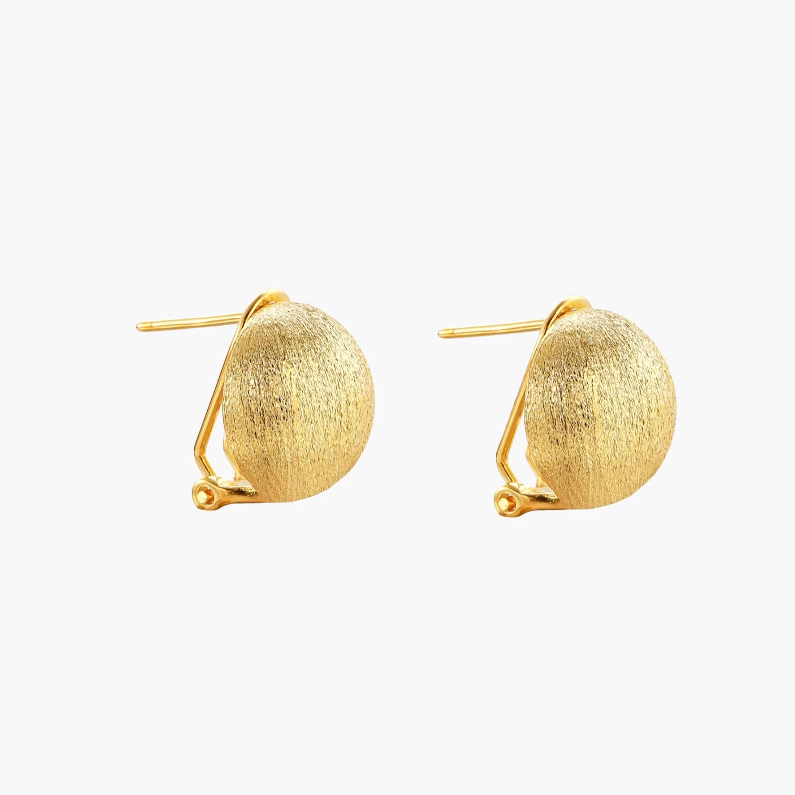 Pair of brushed gold dome earrings with clip backs showing textured matte finish on cream background