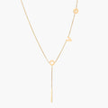 Gold Y-shaped necklace with L-O-V-E letter charms and vertical bar pendant on delicate chain against cream background