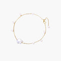 Delicate gold chain bracelet with baroque pearl centerpiece and small freshwater pearls on cream background.