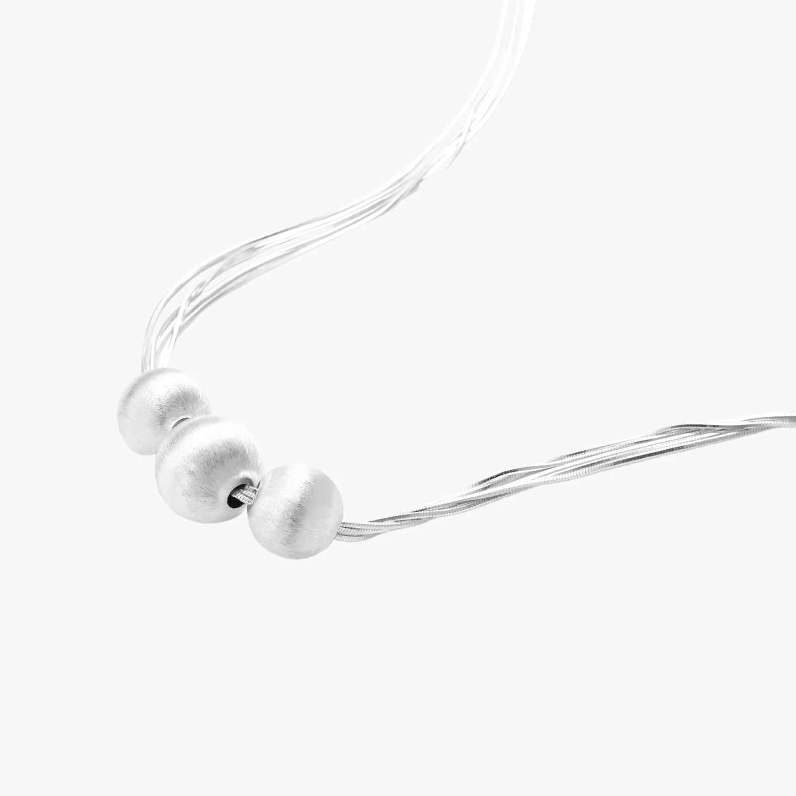 Sterling silver multi-strand necklace with three brushed round beads on cream background