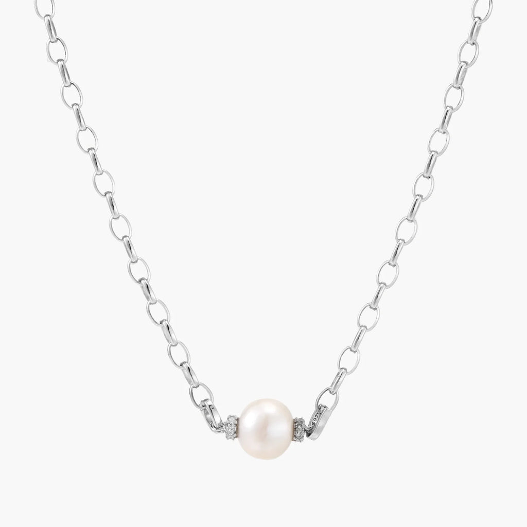 Dainty rhodium-plated silver chain necklace with centered 10mm freshwater pearl and crystal accents on cream background