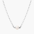 Dainty rhodium-plated silver chain necklace with centered 10mm freshwater pearl and crystal accents on cream background