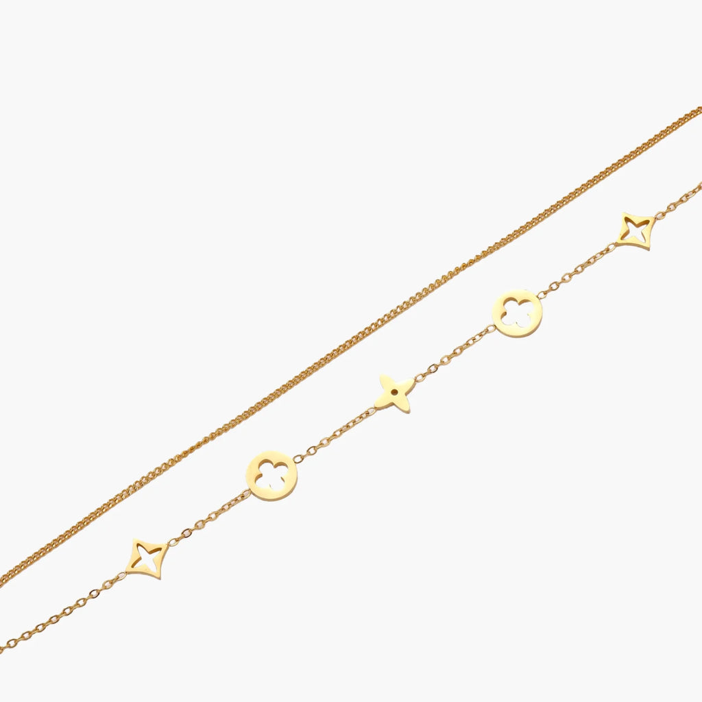 Double-layer gold-plated bracelet with quatrefoil and star charms on cream background, 18K gold finish.