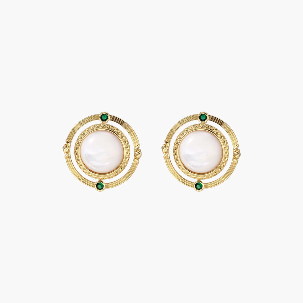 Circular gold stud earrings with iridescent mother-of-pearl center and green zirconia accents on cream background.